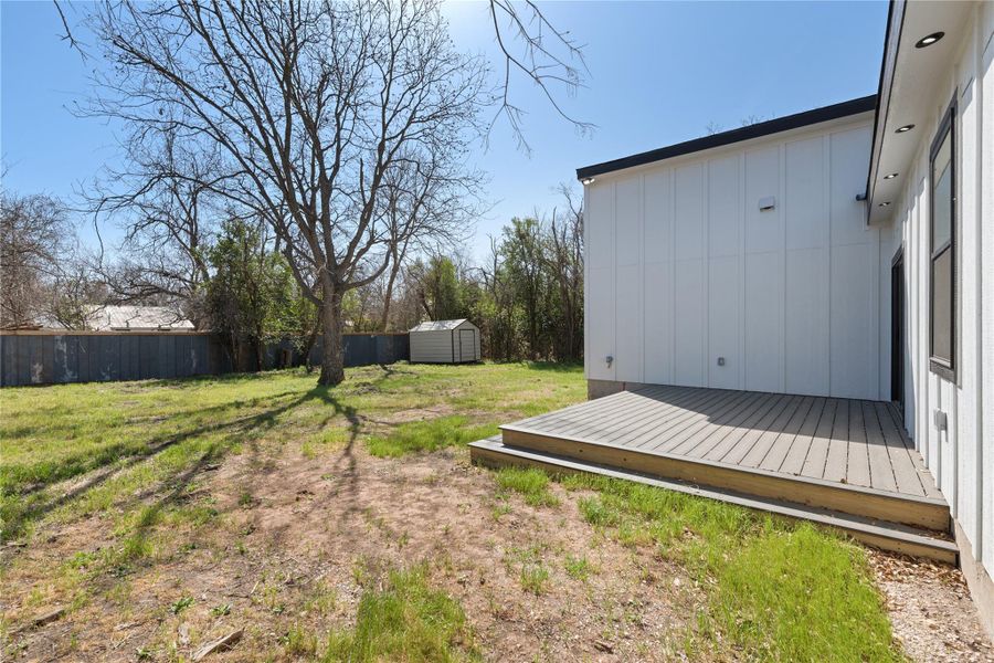 View of yard with a storage shed, fence, an outdoor structure, and a wooden deck
