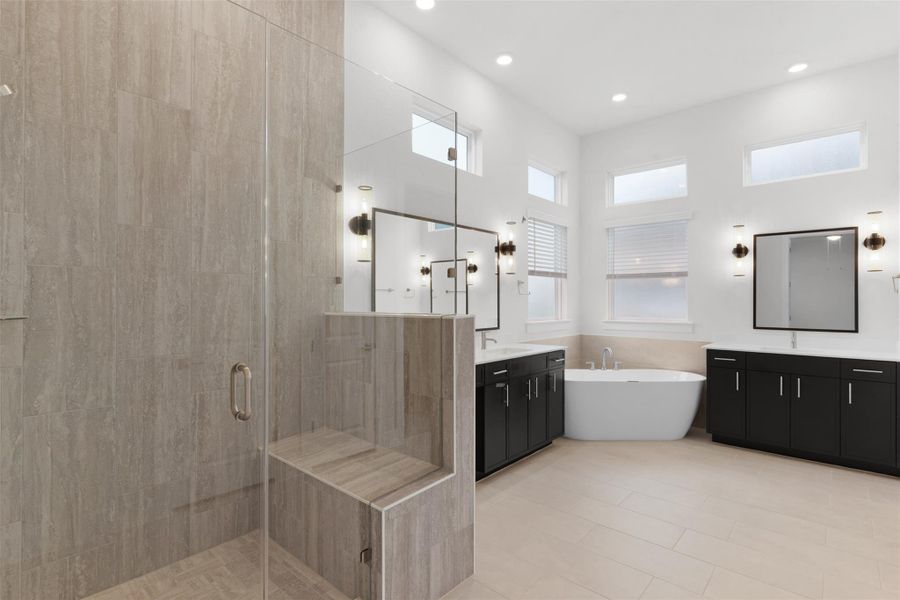 Bathroom featuring a stall shower, two vanities, a soaking tub, and recessed lighting