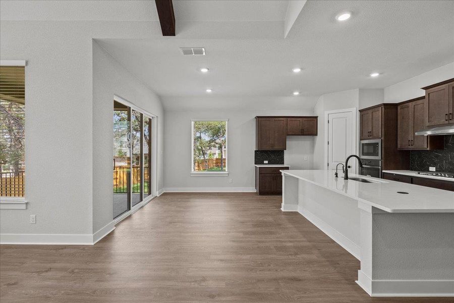 Kitchen with tasteful backsplash, light wood-type flooring, a sink, and recessed lighting Kitchen with tasteful backsplash, light wood-type flooring, a sink, and recessed lighting