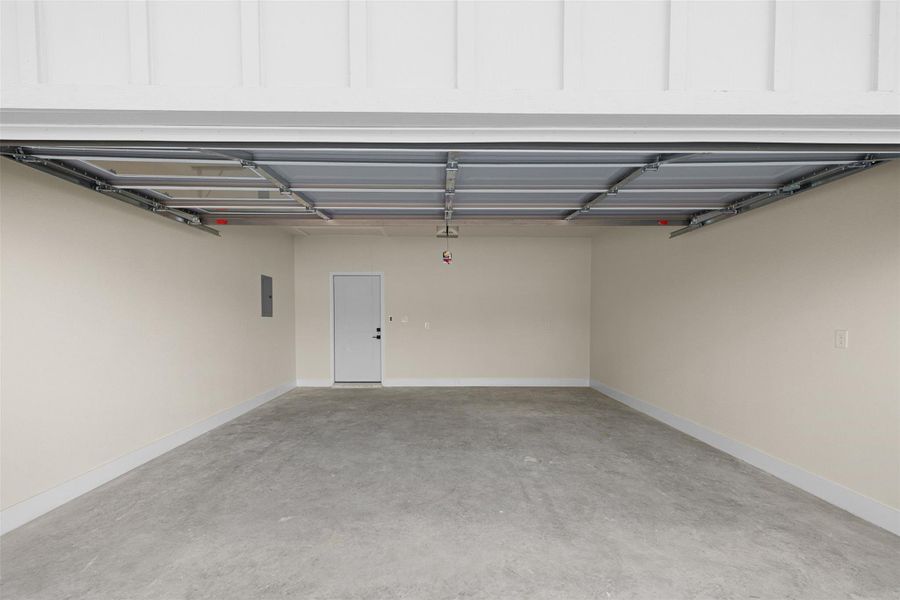 Garage featuring baseboards and electric panel Garage featuring baseboards and electric panel