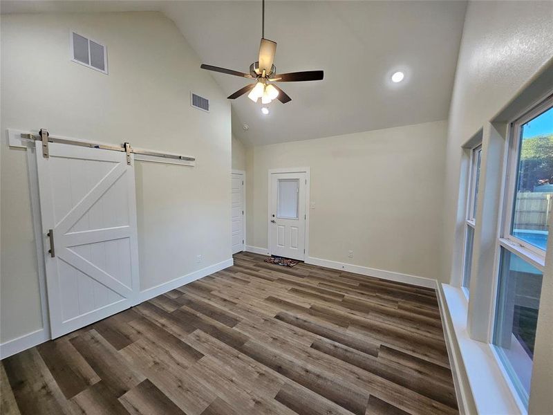 Master bedroom, designer ceiling fan, a barn door, and high vaulted ceiling.