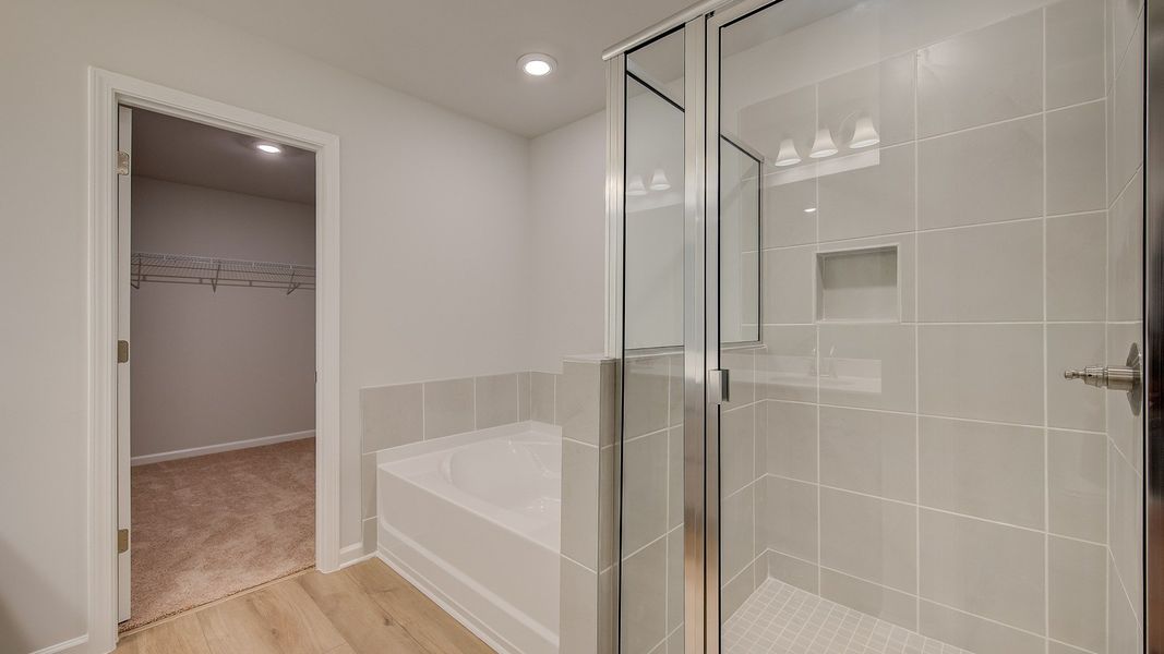 Ridgewood luxury primary bath with spacious tile-wall walk-in shower, tub and walk-in closet at Bowers Farm in McDonough, GA.