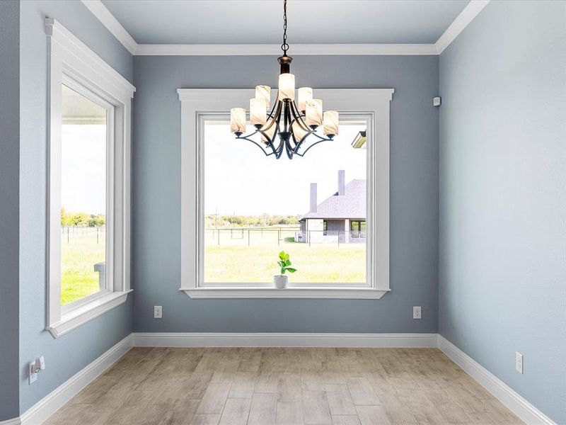 Unfurnished dining area with light wood finished floors, crown molding, and a chandelier Unfurnished dining area with light wood finished floors, crown molding, and a chandelier