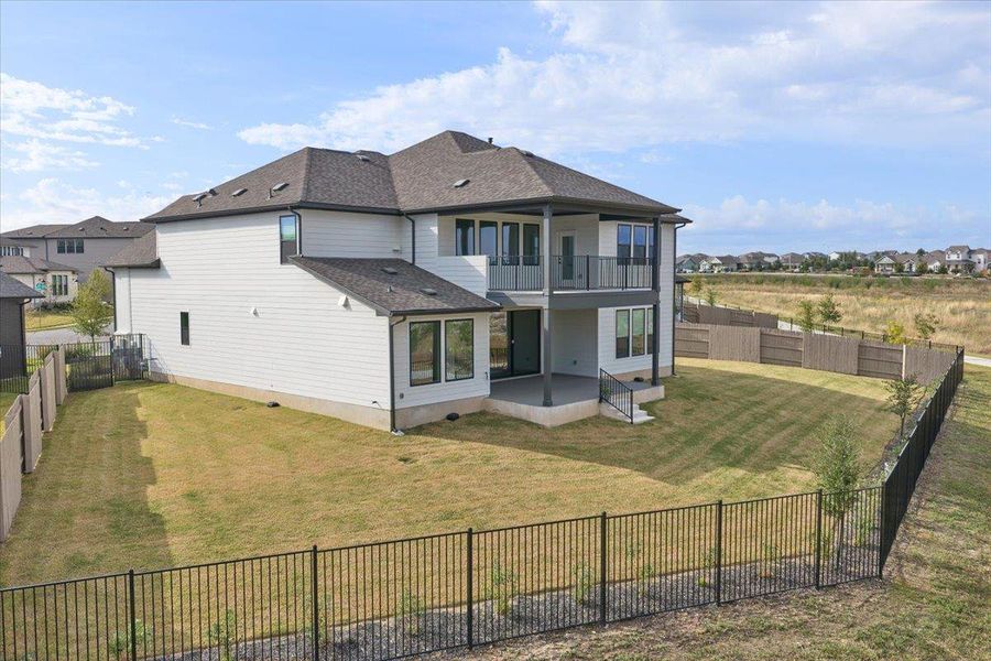 Back of house featuring a patio area, a fenced backyard, a balcony, roof with shingles, and a residential view Back of house featuring a patio area, a fenced backyard, a balcony, roof with shingles, and a residential view