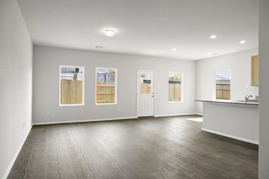 A living room with vinyl flooring, white painted walls, white-framed window, and a white door.