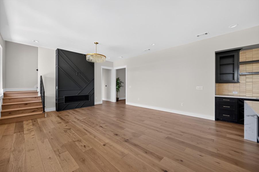 Gleaming hardwood floors and a modern geometric fireplace wall anchor this versatile living space.