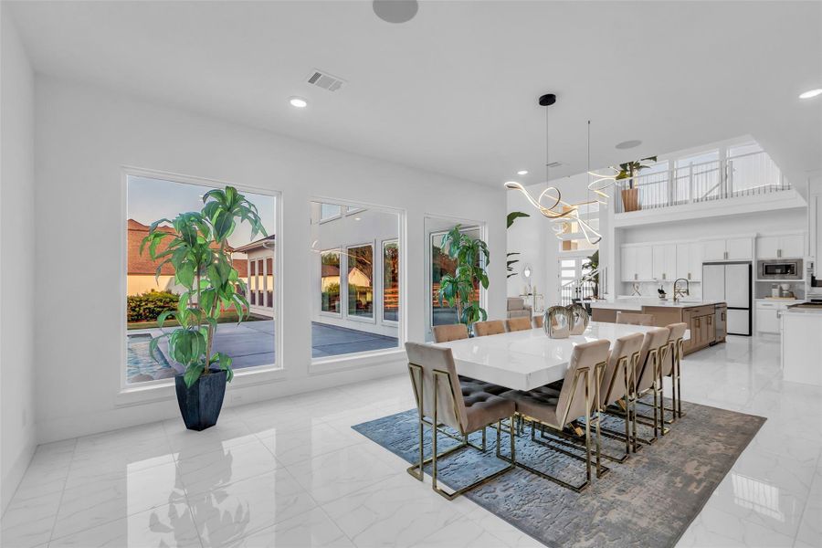 Dining with a View: Floor-to-ceiling windows frame the pool and patio, filling the dining area with natural light. The sleek design flows seamlessly into the chef’s kitchen, creating an elegant setting for gatherings both large and intimate.