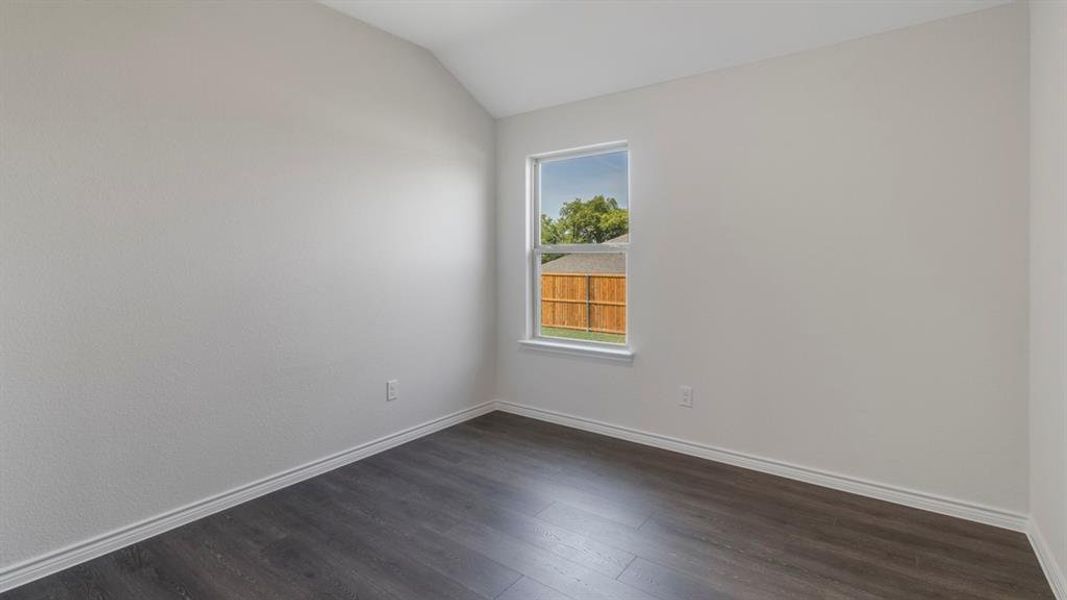 Unfurnished room with dark wood-style floors and lofted ceiling Unfurnished room with dark wood-style floors and lofted ceiling