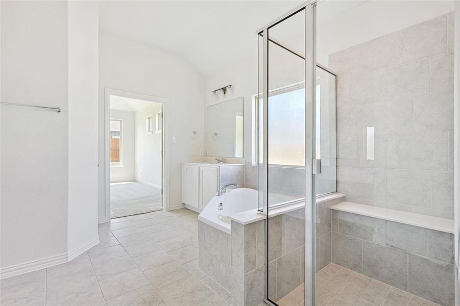 Bathroom featuring tile patterned floors, independent shower and bath, vanity, and a healthy amount of sunlight