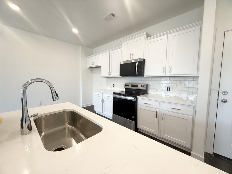 Kitchen with stainless steel appliances, decorative backsplash, white cabinetry, light stone counters, and recessed lighting