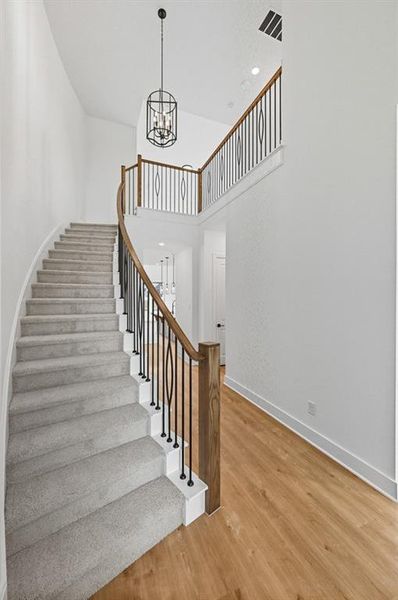 Stairs featuring wood finished floors, a chandelier, a towering ceiling, and recessed lighting Stairs featuring wood finished floors, a chandelier, a towering ceiling, and recessed lighting