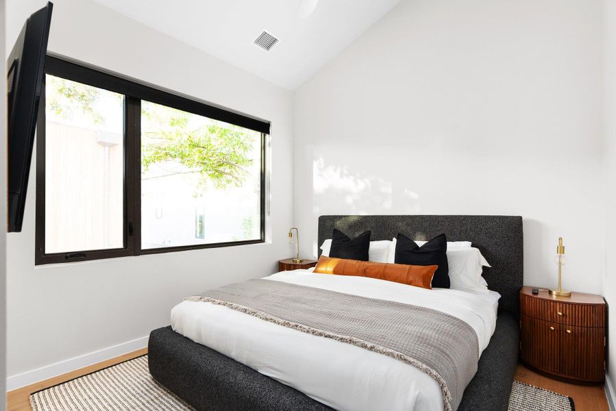 Bedroom with lofted ceiling, light wood-style floors, and multiple windows Bedroom with lofted ceiling, light wood-style floors, and multiple windows