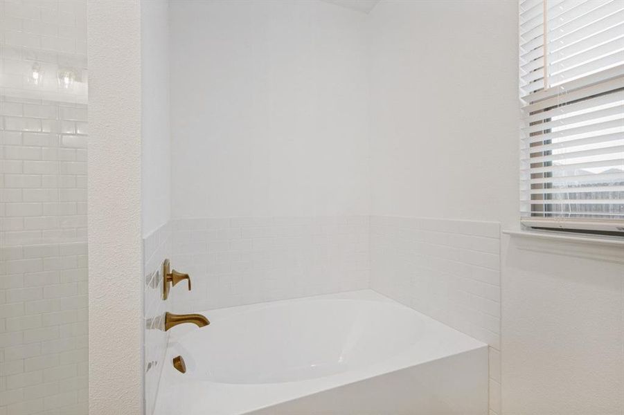 Built-in soaking tub with bronze-finish fixtures and subway tile surround