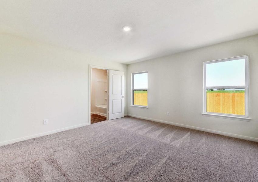 Medina master bedroom with two large side windows, soft brown carpeting, and private bathroom