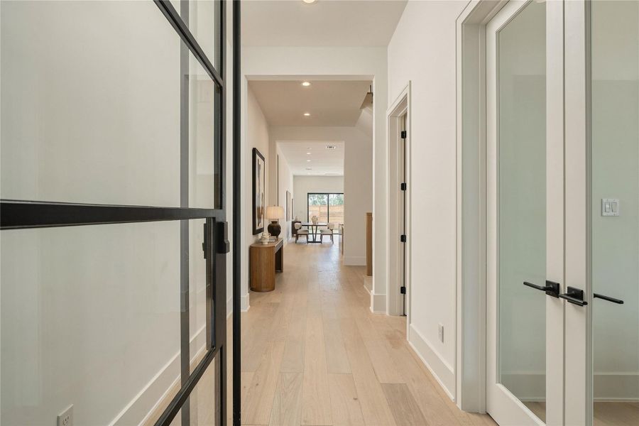 A refined entry corridor sets the tone with engineered oak hardwood flooring, 8-foot solid-core doors, and contrasting black hardware, offering a clean, architectural introduction to the home.