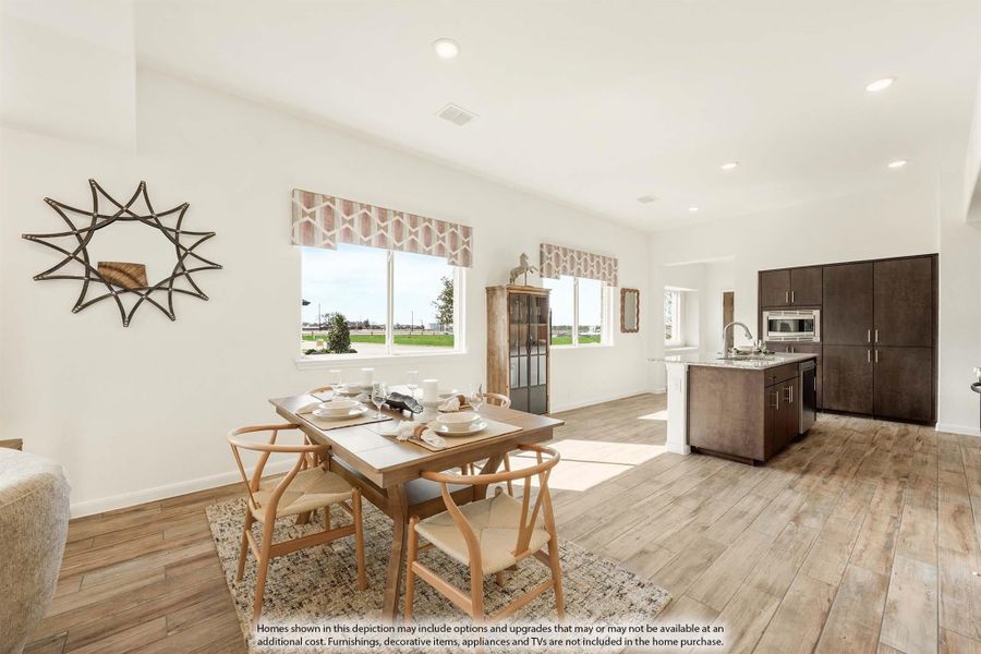 Open-plan dining area with wood table and chairs, connected to kitchen with dark cabinets and wood-look floors