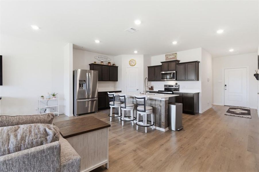 Kitchen with stainless steel appliances, a kitchen breakfast bar, light wood-style flooring, open floor plan, and an island with sink Kitchen with stainless steel appliances, a kitchen breakfast bar, light wood-style flooring, open floor plan, and an island with sink