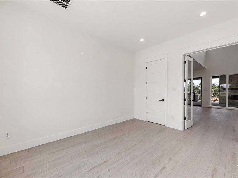 Private office/study featuring a bright and airy design with clean modern finishes, recessed lighting, and elegant glass French doors, creating an ideal space for working from home, meeting clients, or a quiet retreat.