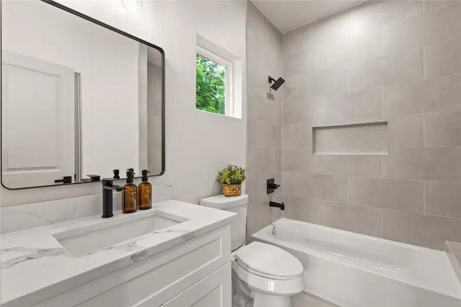 Third bedroom en-suite with quartz vanity, matte black fixtures, and tiled shower/tub Third bedroom en-suite with quartz vanity, matte black fixtures, and tiled shower/tub