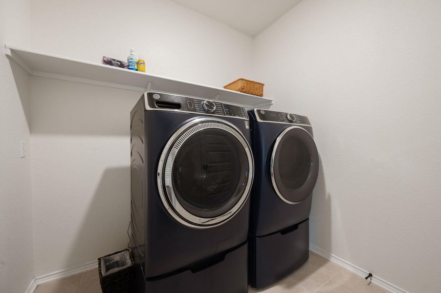 Laundry area with washer and dryer and light tile patterned flooring