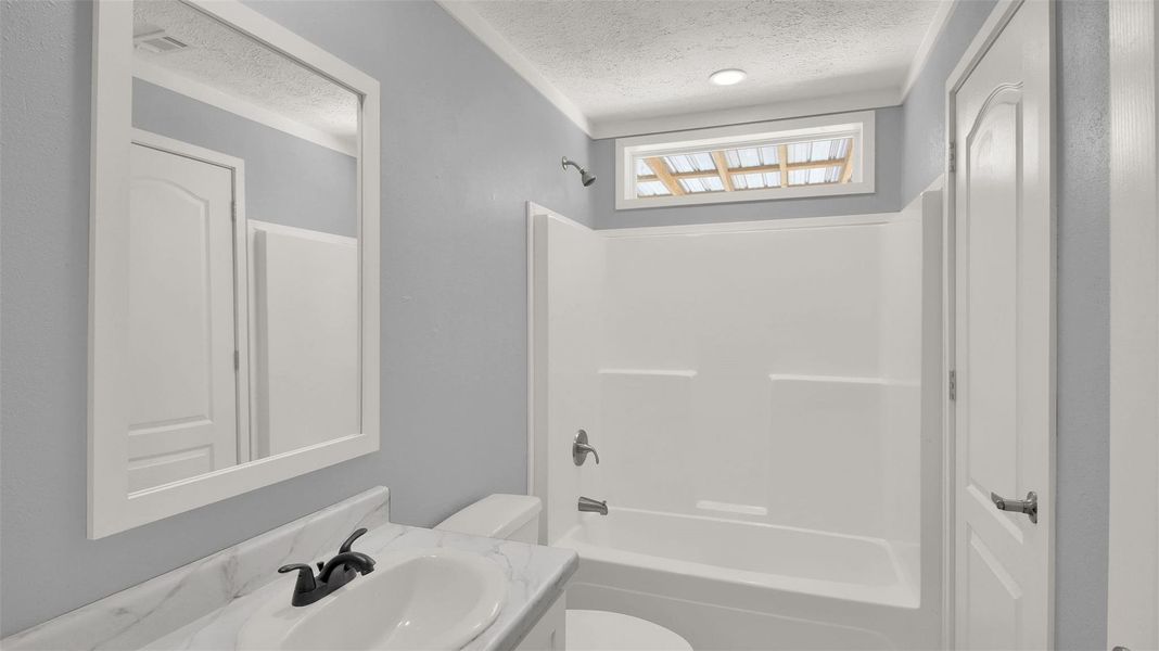 A modern vanity with stone counters complements the shower and tub combination.