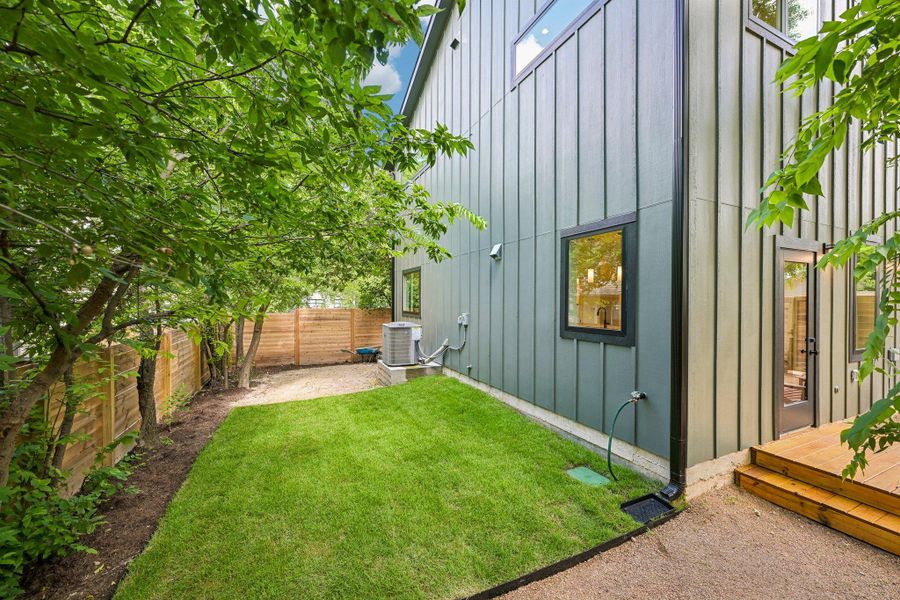 Green landscaping and a wooden privacy fence frame this modern home's exterior. Green landscaping and a wooden privacy fence frame this modern home's exterior.