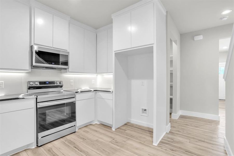 Kitchen featuring light wood-type flooring, white cabinets, and stainless steel appliances