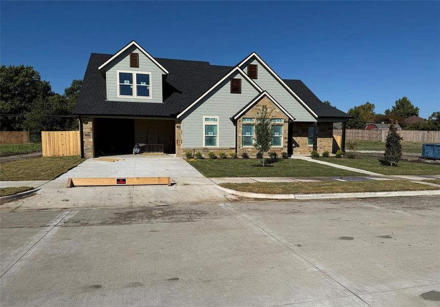 View of front facade featuring driveway, stone siding, a porch, a shingled roof, and a garage View of front facade featuring driveway, stone siding, a porch, a shingled roof, and a garage