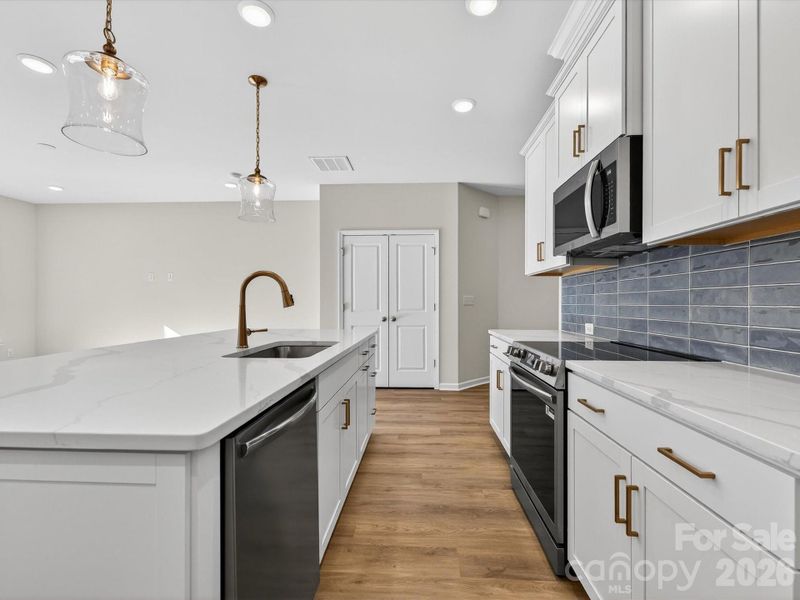 This bright and airy kitchen features an oversized kitchen Island. 42' kitchen cabinets with soft close doors & drawers. Solid shelving in the pantry. Stainless steel Frigidaire appliances with cooking vented to the outside.