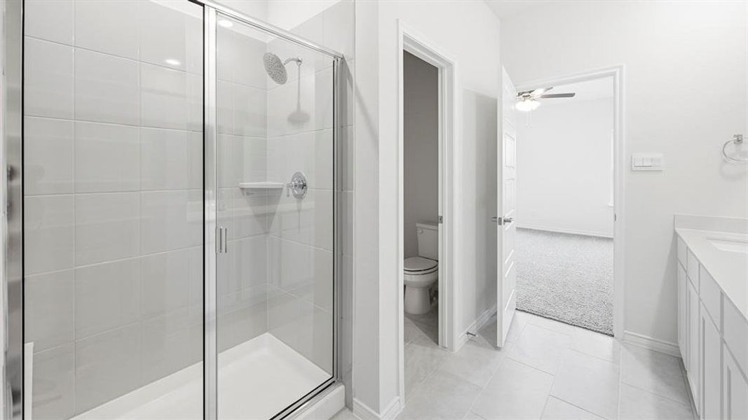 Bathroom featuring vanity, a shower stall, light tile patterned floors, light colored carpet, and ceiling fan