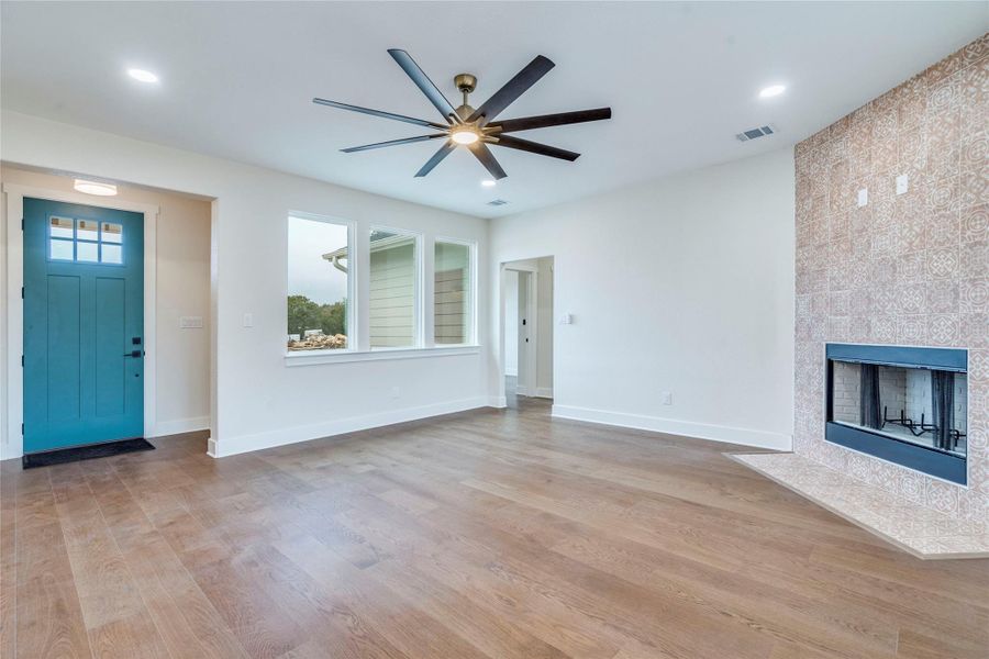 Unfurnished living room featuring light wood-style flooring, a fireplace, healthy amount of natural light, and a ceiling fan