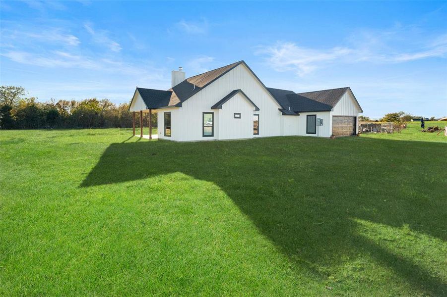 Rear view of house featuring a garage and a yard