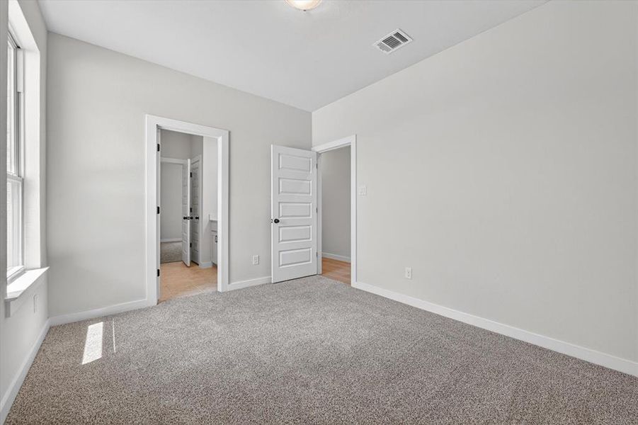 Spacious room with light gray wall paint, gray carpet, white trim, and a window with a white frame