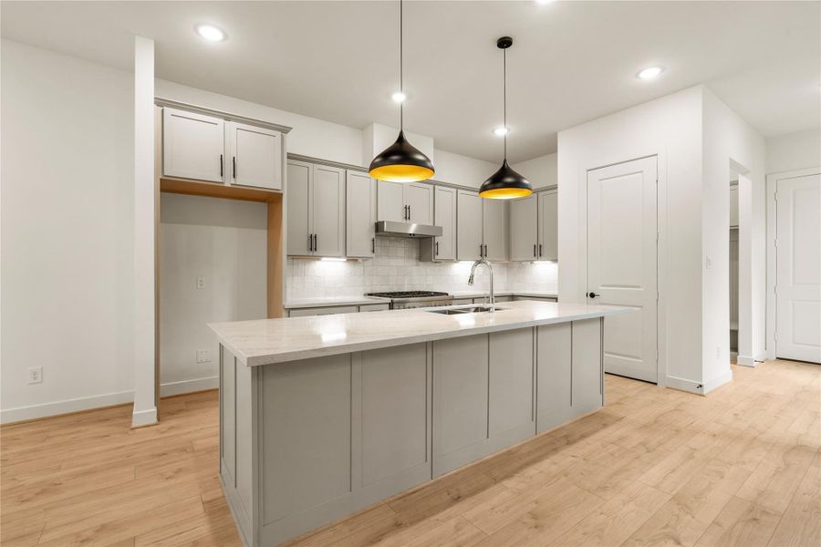 Open-concept kitchen view — fluid connection from the prep island to the main floor landing and adjacent pantry access.