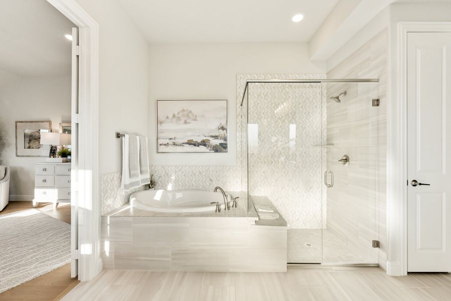 Master bathroom with soaking tub, glass-enclosed shower, and white tile walls open to bedroom