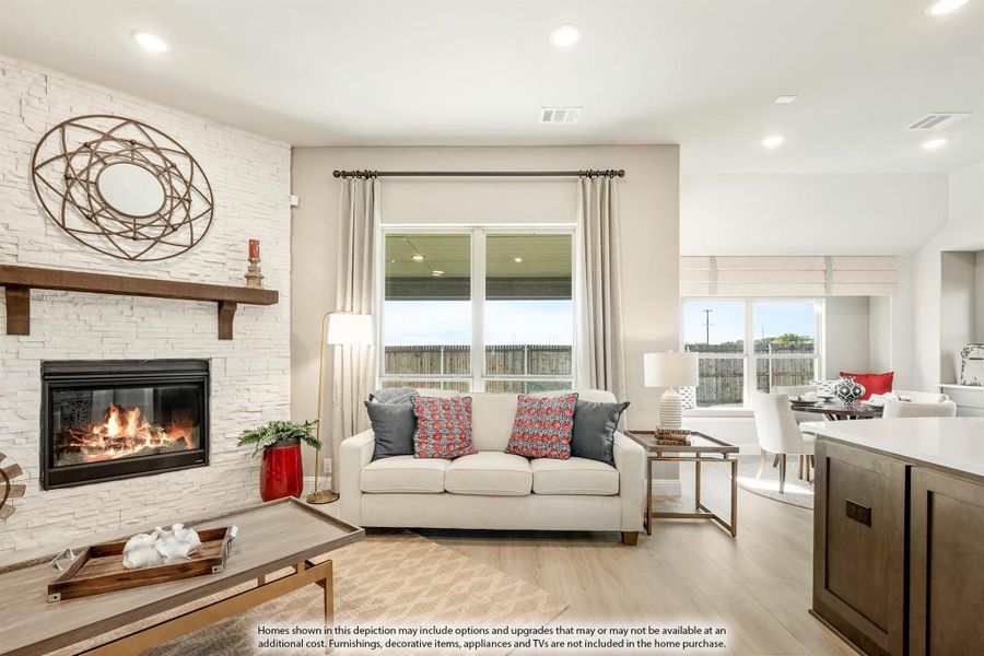 Open living room with white stone fireplace, light wood floors, and cream sofa with colorful pillows Open living room with white stone fireplace, light wood floors, and cream sofa with colorful pillows