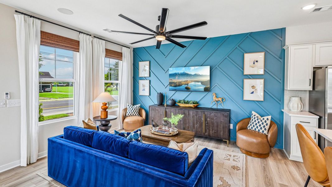 Gathering room with ceiling fan, hard surface flooring, and accent wall