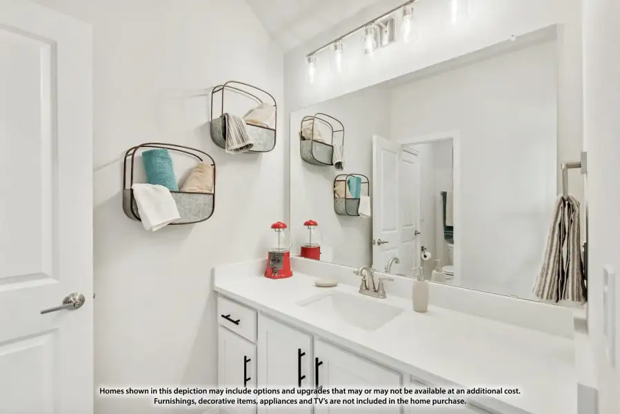 Bathroom with white vanity, double sink, large mirror, and wall-mounted wire storage baskets with towels