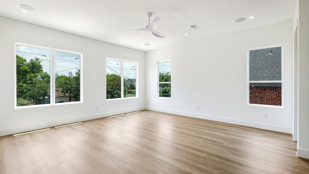 Empty room with light hardwood / wood-style flooring, plenty of natural light, and ceiling fan