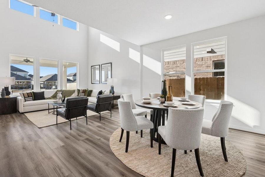 Dining area featuring light wood-style flooring, a towering ceiling, and recessed lighting Dining area featuring light wood-style flooring, a towering ceiling, and recessed lighting