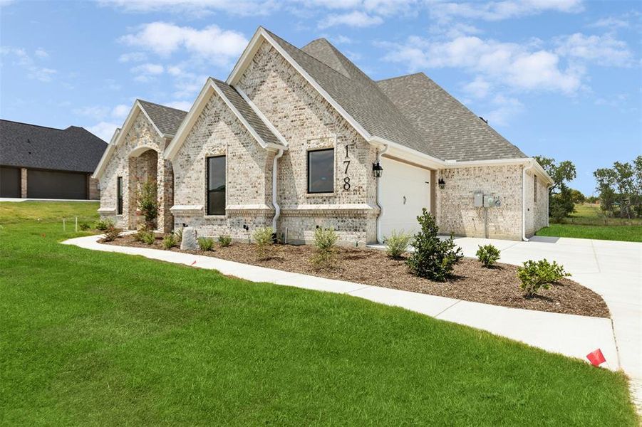 French provincial home featuring a garage and a front yard