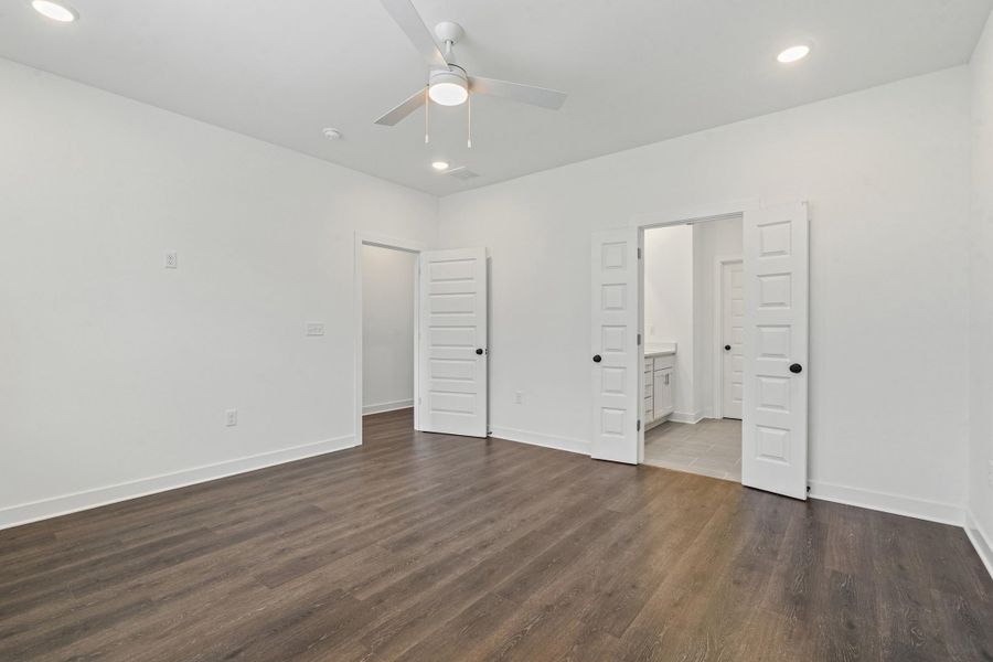 Spacious room featuring wood-finish flooring, white walls, and a ceiling fan with integrated lighting