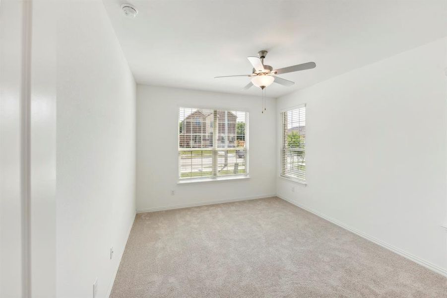 Empty room with ceiling fan and light colored carpet