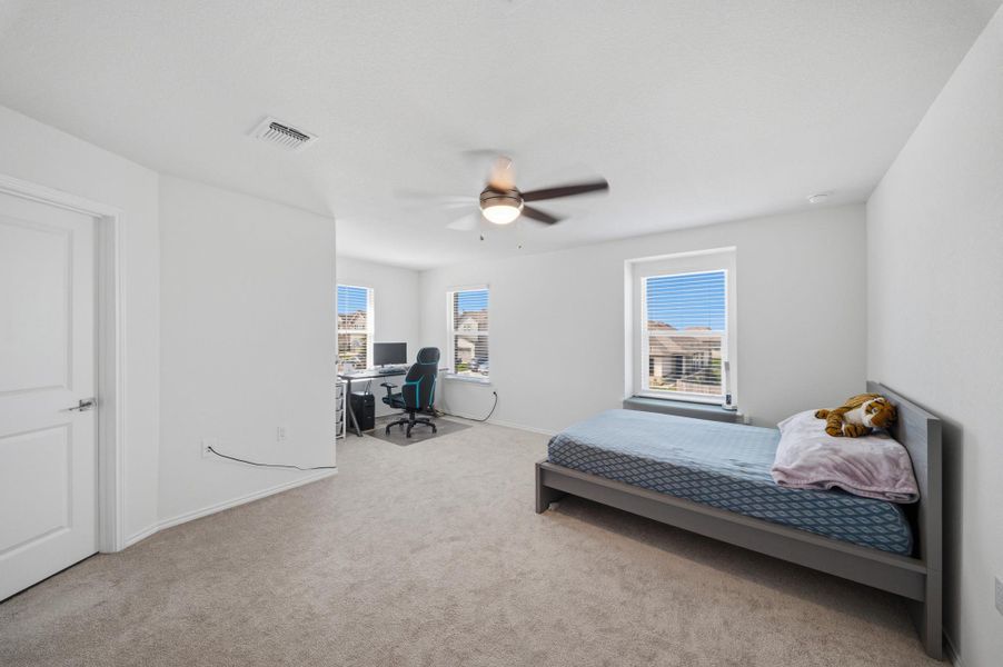 A quiet bedroom offering comfort and a functional workspace, with abundant natural light from multiple windows. A quiet bedroom offering comfort and a functional workspace, with abundant natural light from multiple windows.