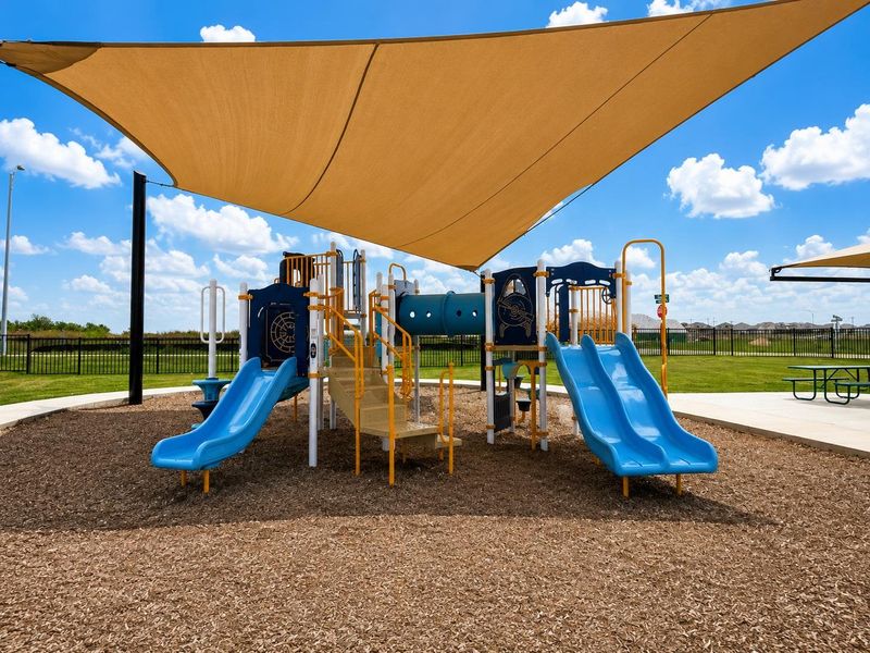 A well-maintained community playground awaits, featuring shaded play structures and open green space.