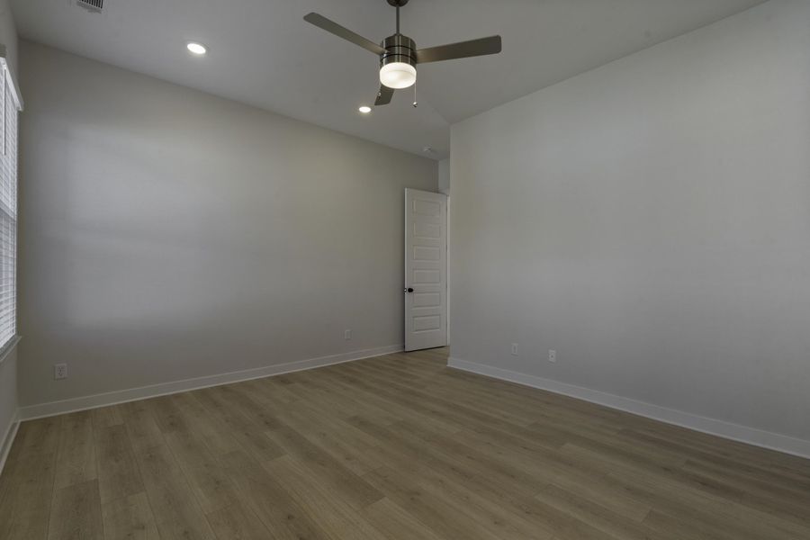 Vaulted ceiling with a ceiling fan, recessed lighting, wood-finish flooring, and a paneled door