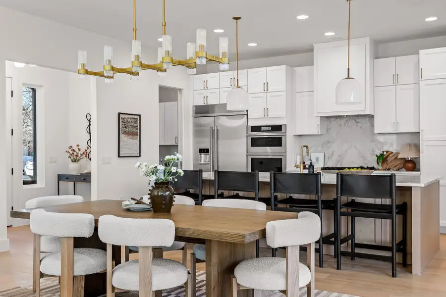Kitchen with white cabinetry, light wood-style floors, stainless steel appliances, decorative backsplash, and a center island