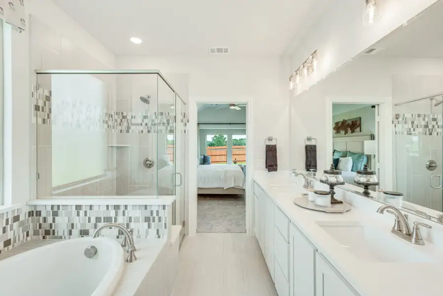 Master bathroom with double vanity, soaking tub, glass shower, and mosaic tile accents