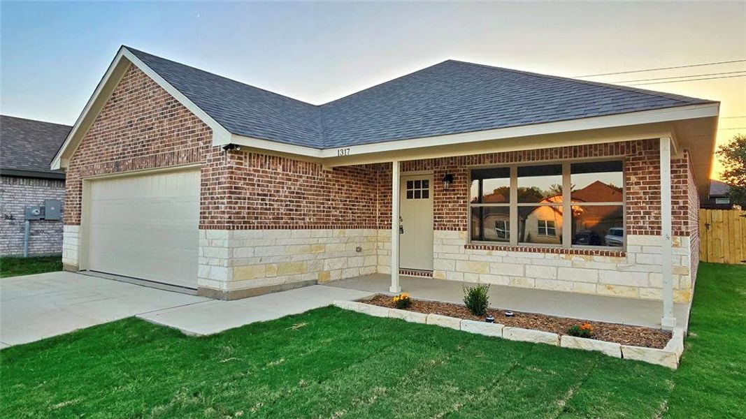 Single story home featuring a shingled roof, brick siding, and an attached garage