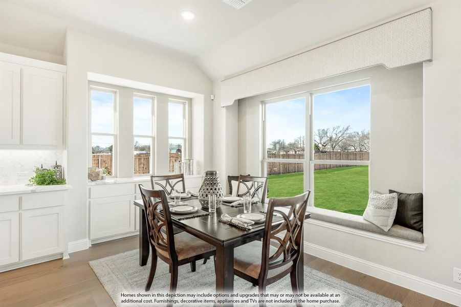 Bright dining area with dark wood table, window seat, and large windows overlooking a backyard